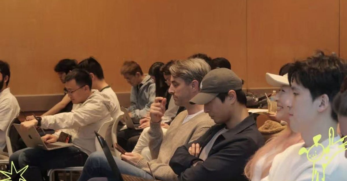 Engineers and founders watch the kickoff from their seats with laptops open